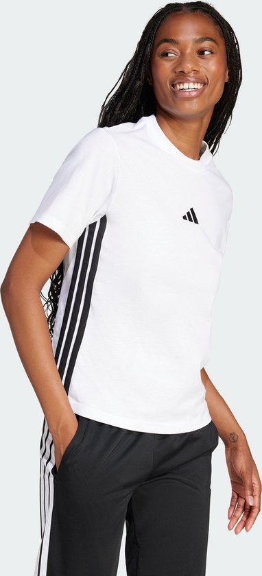 Model met gevlochten haar, draagt een wit t-shirt met zwarte Adidas strepen op de zijkant.