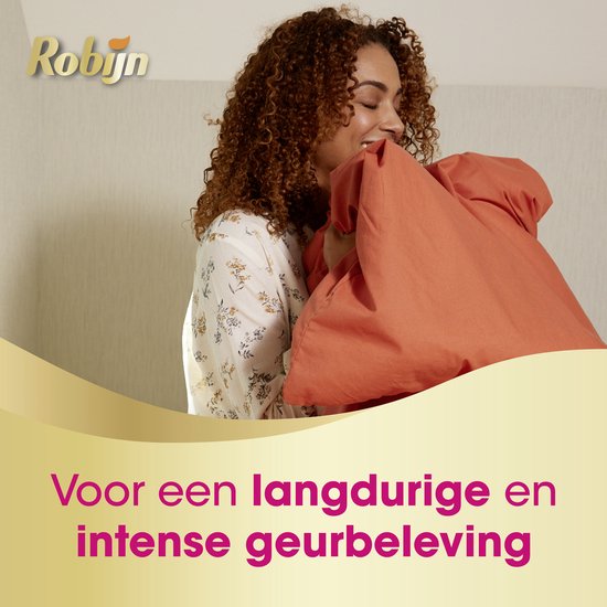Een vrouw met krullend haar ruikt aan een oranje dekbed, met de tekst 'Voor een langdurige en intense geurbeleving'.