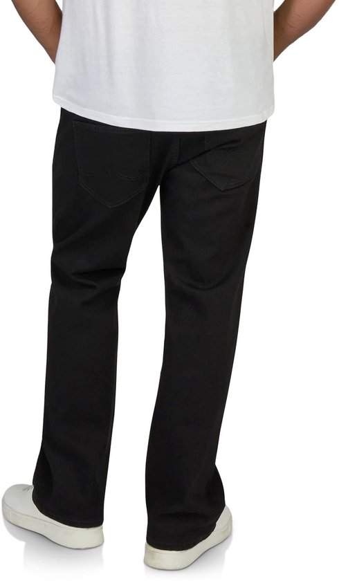 Achterkant van een zwarte jeans met bootcut pasvorm, gedragen door een man met witte sneakers.