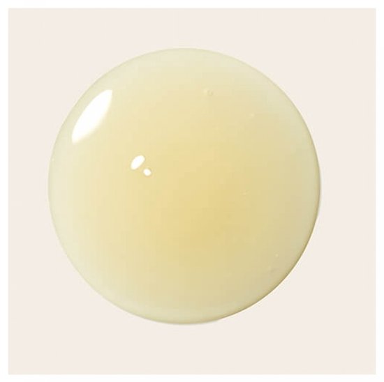 Een druppel lichtgele vloeistof met luchtbelletjes op een witte achtergrond.