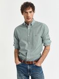 Man met groene gestreepte blouse, spijkerbroek en bruine riem