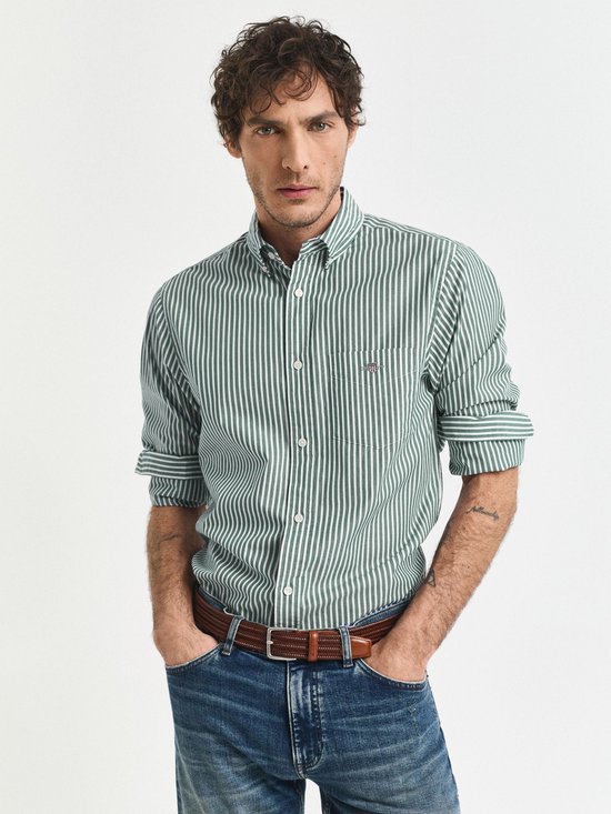 Man met groene gestreepte blouse, spijkerbroek en bruine riem
