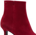 Close-up van een rode suède enkellaars met een stilettohak en zijkant ritssluiting. Merklogo zichtbaar.