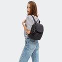 Vrouw met gestreept shirt en spijkerbroek draagt een zwarte Kipling rugzak.