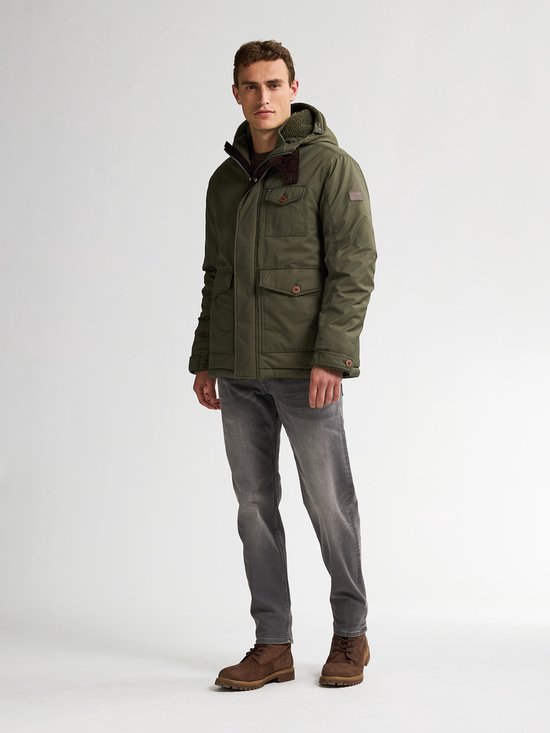 Man in groene parka met capuchon en grijze jeans.