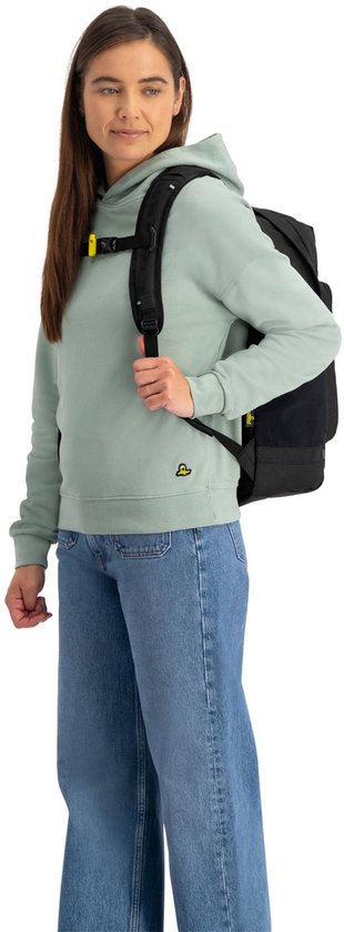 Vrouw met lichtgroene hoodie en spijkerbroek, draagt een zwarte rugzak.