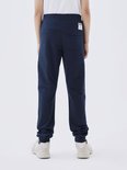 Achterkant jongen in donkerblauwe joggingbroek.