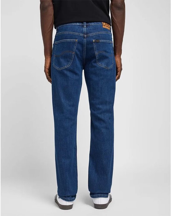 De achterkant van een man in een rechte, donkerblauwe jeans van Lee. De jeans heeft een klassieke pasvorm en een bruin label op de achterkant.