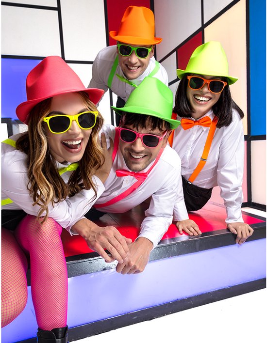 Groep van vier mensen in witte overhemden met felgekleurde hoeden, bretels en zonnebrillen.