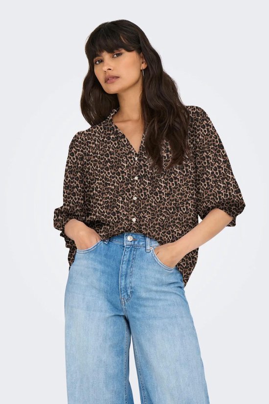 Model draagt een bruine blouse met luipaardprint, driekwart mouwen en lichtblauwe wijde jeans.