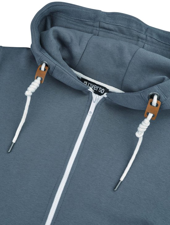 Detail van de capuchon en kraag van een blauwgrijze hoodie met rits, witte koordjes en bruine details.
