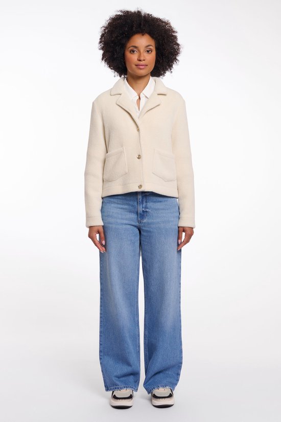 Mannequin portant une veste courte couleur crème à col revers et boutons dorés, avec un jean.