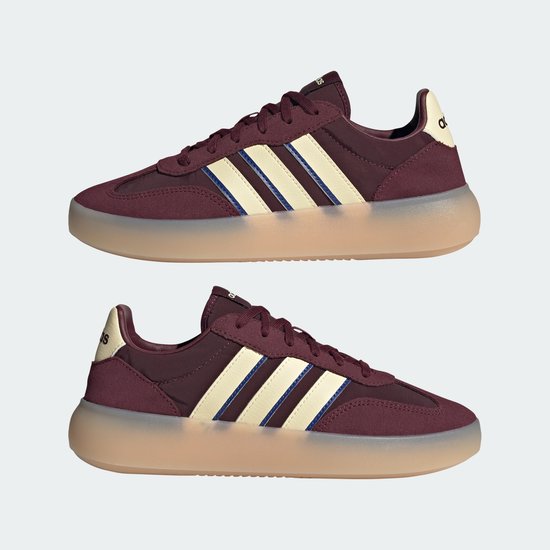 Paar bordeauxrode sneakers met beige en blauwe strepen, beige zolen.
