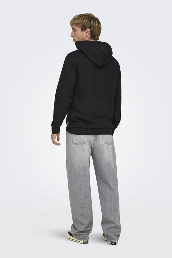 Man met blonde haren, zijaanzicht, draagt een zwarte hoodie met capuchon en grijze jeans.