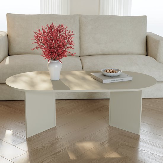 Ovale salontafel in havermoutkleur met een vaas met rode bloemen en een boek.