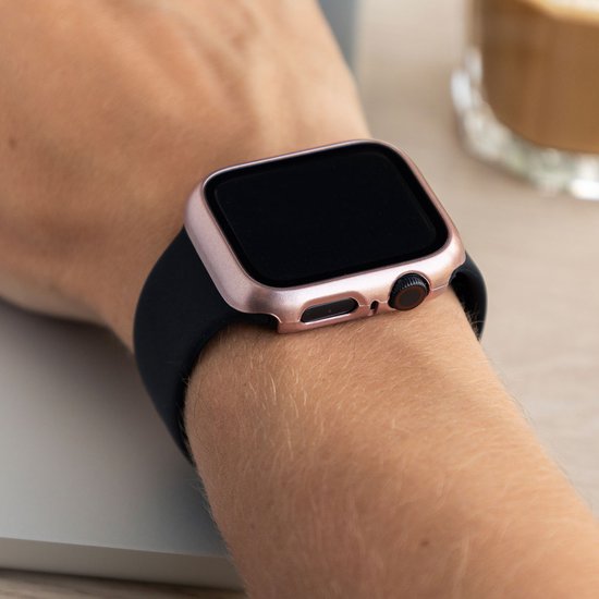 Rosegouden smartwatch case om een Apple Watch met zwart bandje, gedragen om een pols.