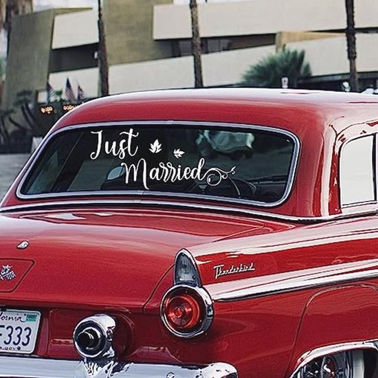 Texte blanc 'Just Married' sur la lunette arrière d'une voiture rouge vintage.