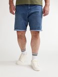 Detail van een man die een blauwe denim short met opgerolde zoom draagt, met witte sokken met zwarte strepen en witte sneakers.