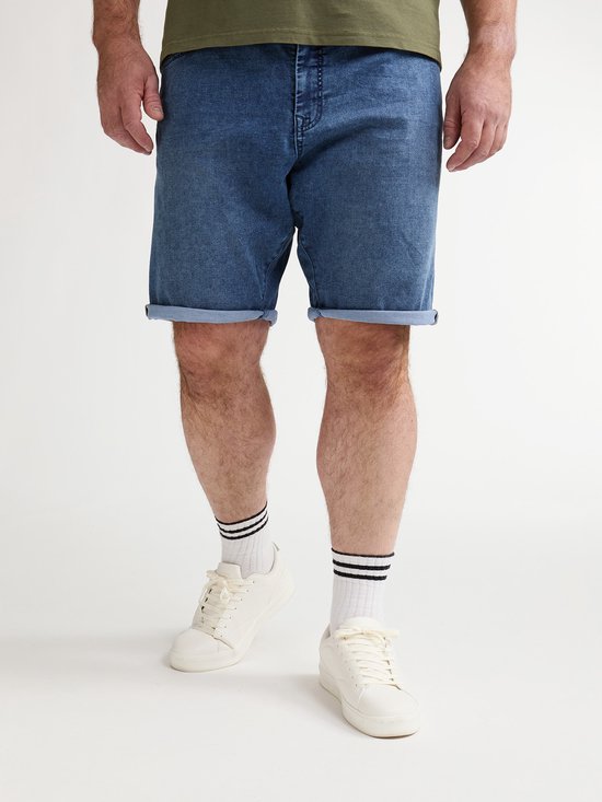 Detail van een man die een blauwe denim short met opgerolde zoom draagt, met witte sokken met zwarte strepen en witte sneakers.