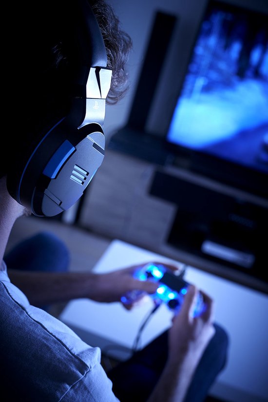 Close-up van een persoon met een zwarte en blauwe gaming headset, spelend met een blauw verlichte controller.