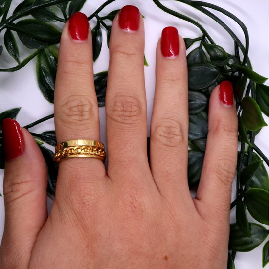 Gouden draairing met schakelketting en Romeinse cijfers, gedragen op een hand met rode nagellak.