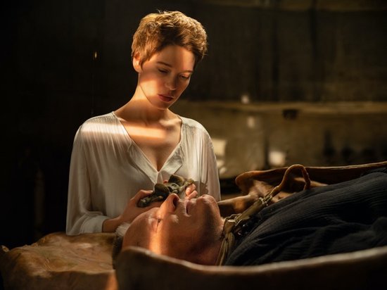 Léa Seydoux in een wit gewaad houdt een metalen object vast boven het gezicht van Viggo Mortensen.