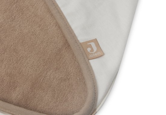 Gros plan de l'intérieur beige et doux d'une cape de bain avec un bord beige et une étiquette Jollein.