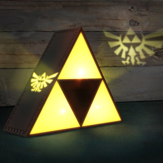 Gele driehoekige lamp met Triforce-symbool, werpt Hylian crest-schaduw op houten achtergrond.
