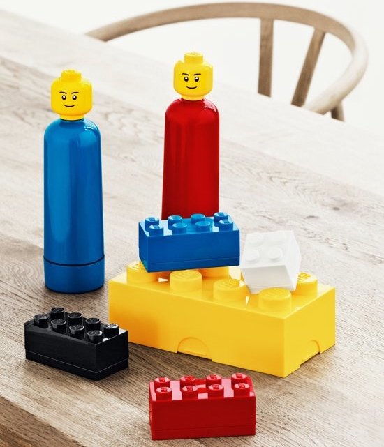 Blauwe en rode LEGO bidons met gele poppetjesdoppen, omringd door LEGO stenen.