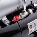 Zilverkleurig koppeldeel met rode ontluchtingshendel op de zwarte tank van de airbrush compressor.