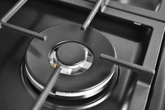 Gedetailleerde opname van een zwarte gasbrander met gietijzeren panondersteuning.
