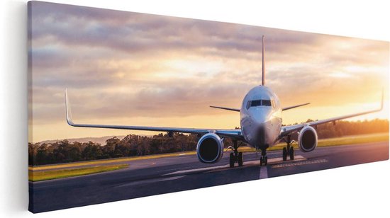 Une toile représentant un avion sur la piste au coucher du soleil.