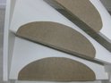 Drie beige halvemaanvormige trapmatten op witte traptreden.