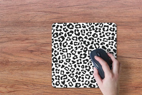 Hand gebruikt een muis op een muismat met zwart-witte panterprint.