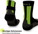 Zwarte sportsokken met felgroene accenten en stippen op de hiel, met "Weniger Schmerzen" tekst.