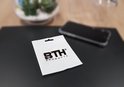 Witte verpakking met het BTH PRODUCTS logo, met een telefoon en plant op de achtergrond.