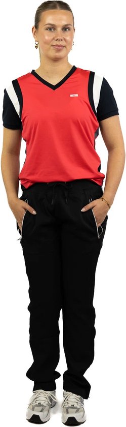 Model draagt een rode sporttop met donkerblauwe mouwen en witte accenten, met een zwarte trainingsbroek.