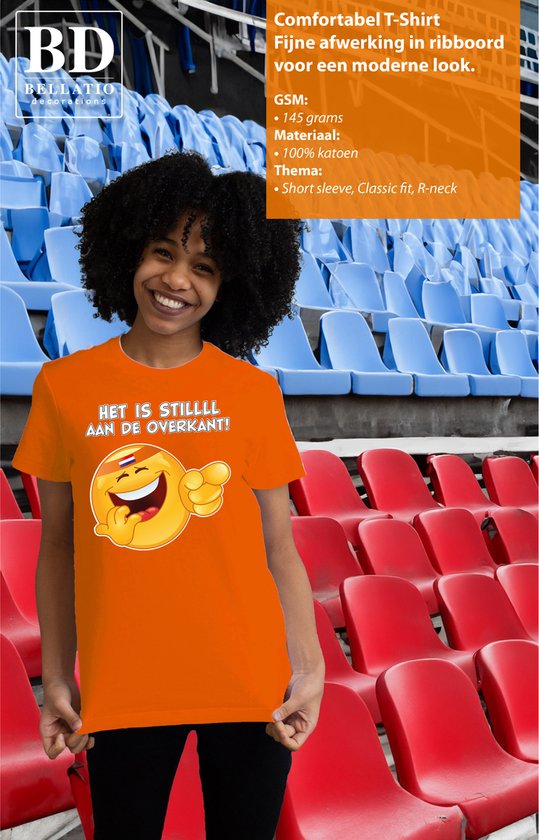 Oranje T-shirt met opdruk van lachende emoji met Nederlandse vlag en tekst 'HET IS STILLLL AAN DE OVERKANT!'. Model in oranje T-shirt op tribune.