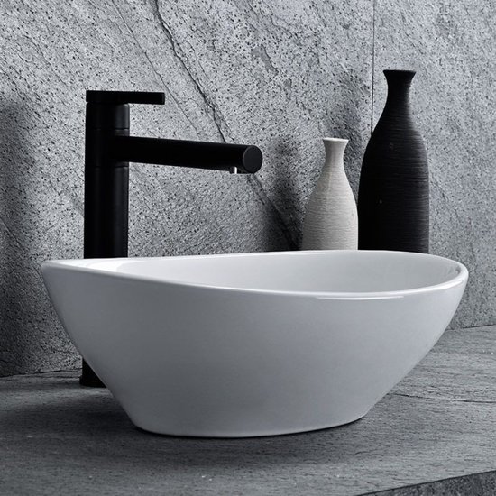 Lavabo blanc ovale à poser avec robinet noir, avec vases décoratifs.