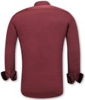 Dos d'une chemise bordeaux en satin, coupe ajustée. Manches retroussées.