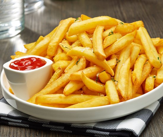 Een schaal met goudbruine, knapperige frietjes, bijgerecht met ketchup.
