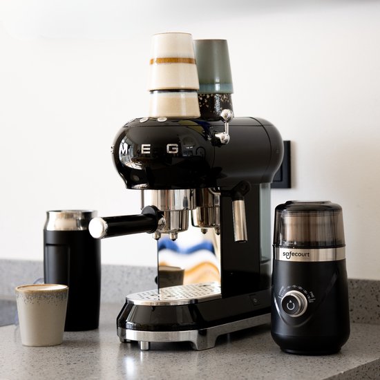 Zwarte Safecourt koffiemolen naast een zwarte espressomachine en mokken.