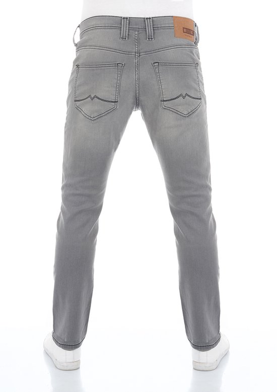 Achterkant van een man in een grijze jeansbroek, staand op witte sneakers.