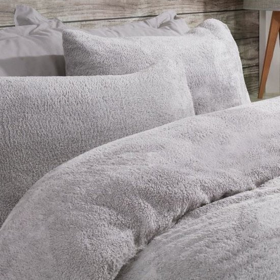 Grijze teddy fleece dekbedovertrek en kussens in een slaapkamer met houten accenten.