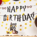 Een verjaardagsbanner met tovenaars thema, taartdecoratie en sterrenslingers.