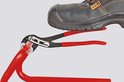 Knipex 88 01 250 waterpomptang met rode handvatten, klemt een rode buis, onder een veiligheidsschoen.