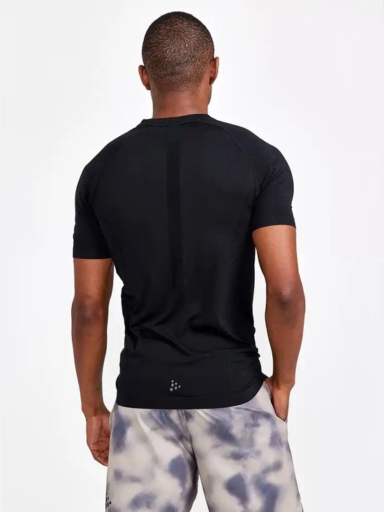 Achterkant van een man in zwart Craft sportshirt met korte mouwen. Gestructureerde stof op de schouders en mouwen, met logo op de rug.